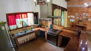 A kitchen with a stove, sink, and wooden counter. - Casa San Isidro is a sparkling clean, and family friendly house (Copán Ruinas)