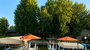 An outdoor patio area with Adirondack chairs, a fire pit, and covered umbrellas. - Waterfront Arnolds Park 4BR Dock, Boat Slip, Kayaks & Paddleboards (Arnolds Park)