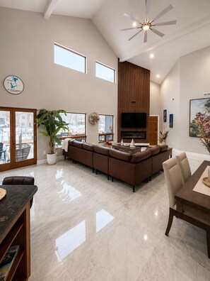A spacious living room with a large sectional sofa, a flat-screen TV, and a fireplace. - Okoboji Waterfront 5BR• Private Dock, Boat Slip, Kayaks & Paddleboards (Arnolds Park)