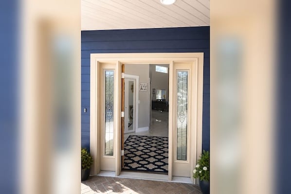 A house entrance with a glass door, a patterned rug, and a potted plant. - Okoboji Waterfront 5BR• Private Dock, Boat Slip, Kayaks & Paddleboards (Arnolds Park)