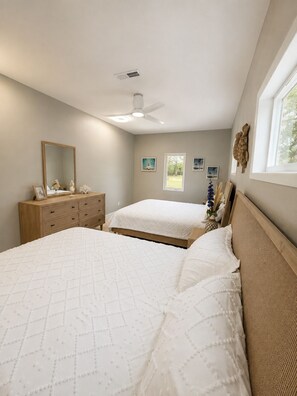 Ein Schlafzimmer mit zwei Betten, einem Schminktisch, einem Deckenventilator und einem Fenster.