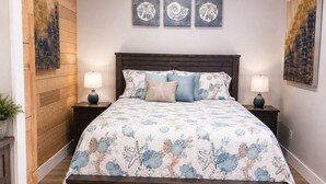 A bedroom with a wooden headboard, a floral bedspread, and two wall-mounted lamps. - Waterfront Arnolds Park 4BR Dock, Boat Slip, Kayaks & Paddleboards (Arnolds Park)