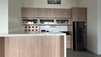 Une cuisine moderne avec des meubles en bois, un plan de travail en marbre et un réfrigérateur noir.
