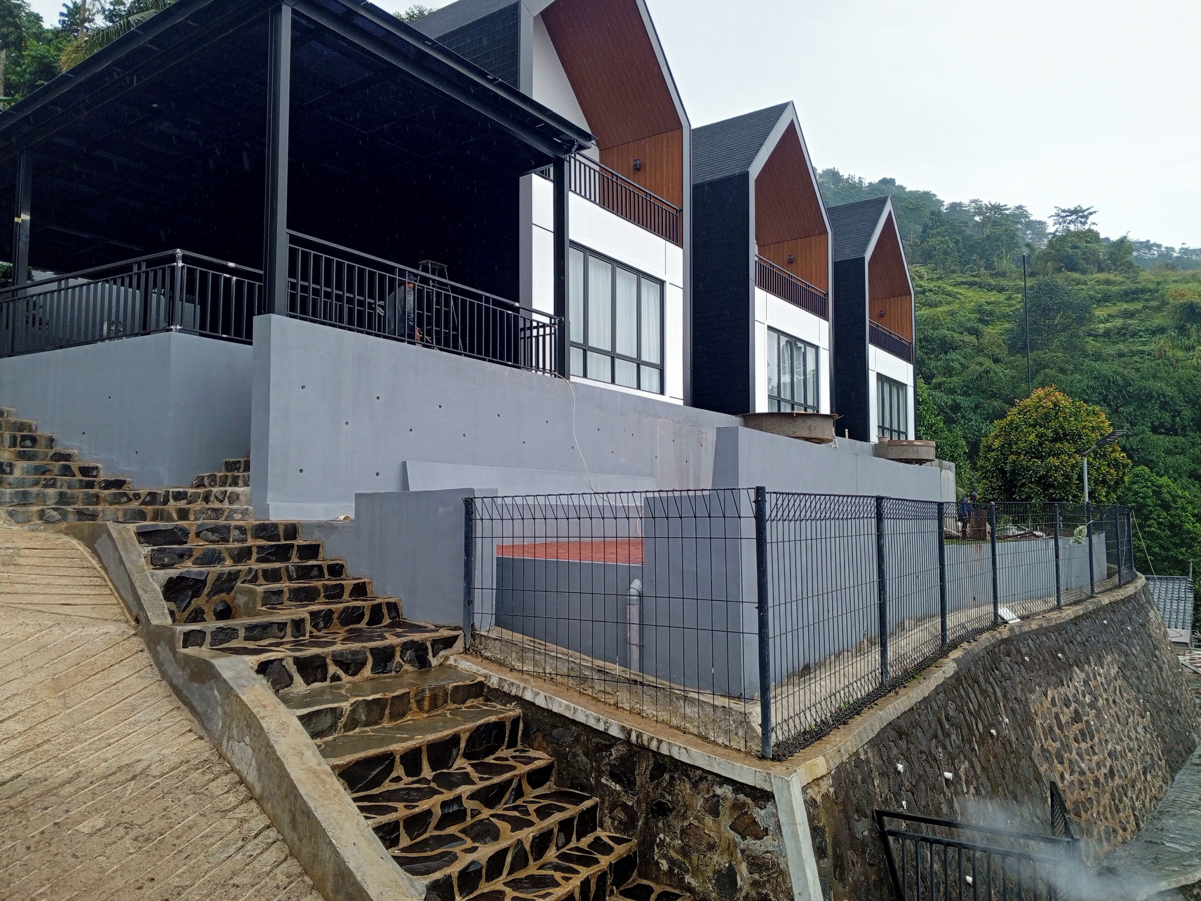 Un bâtiment moderne doté d’un escalier en pierre menant à un espace abrité, agrémenté d’une rambarde en métal.