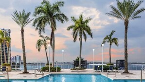 A swimming pool with palm trees and a view of the city skyline. - Harbor View Elite-Luxury Apartment-Amazing Views (Fort Myers)