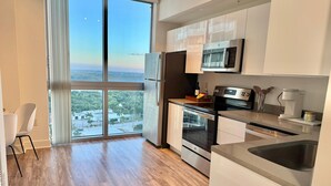 A modern kitchen with a large window, stainless steel appliances, and a view of a cityscape. - Harbor View Elite-Luxury Apartment-Amazing Views (Fort Myers)