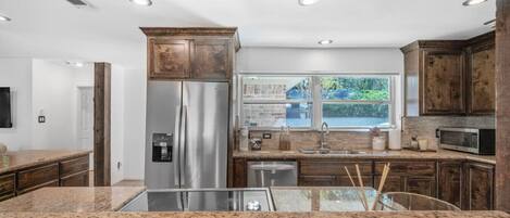 Una cocina moderna con encimeras de granito, electrodomésticos de acero inoxidable y armarios de madera.
