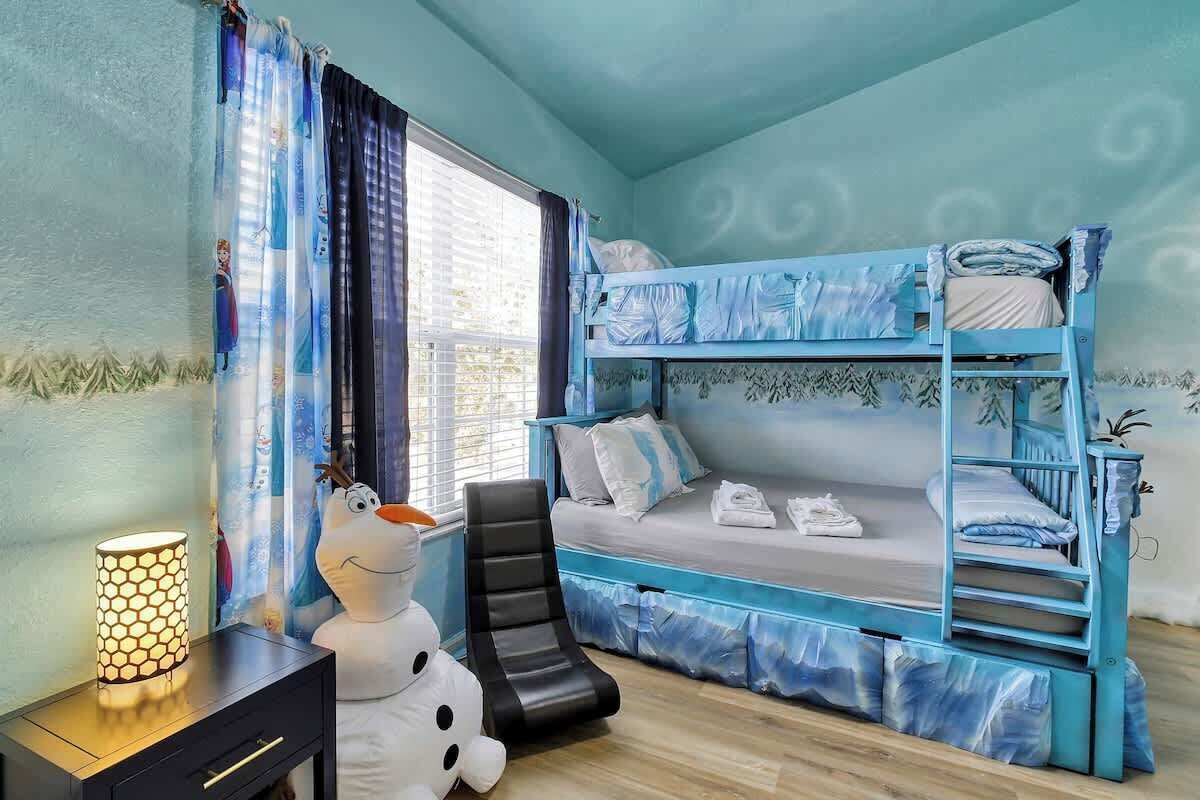 A room with a bunk bed, a desk with a lamp, and a plush toy.