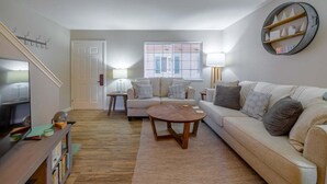 Ein Wohnzimmer mit einer Couch, einem Couchtisch, einem Fernseher und Bücherregalen.