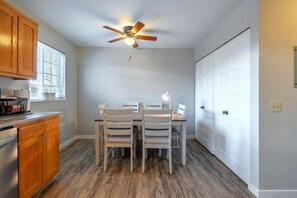 A kitchen with wooden cabinets, a dining table with chairs, a ceiling fan, and a window with blinds. - Yodel Haus -  A Walkable Leavenworth Stay (Leavenworth)