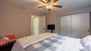 Ein Schlafzimmer mit einem Bett, einem Deckenventilator, einem Fernseher und zwei Schränken.