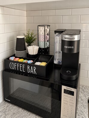 Una cafetería con una cafetera Keurig, un portavasos para café y una variedad de cápsulas de café.