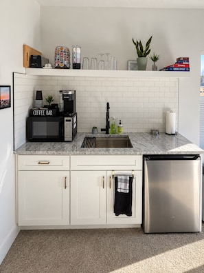Una cocina moderna con armarios blancos, una barra de café, un lavamanos y un lavavajillas.