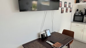 Una sala de estar moderna con un televisor de pantalla plana montado en la pared, una zona de bar con café y una mesa de comedor con sillas.