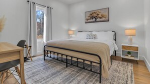 A bedroom with a bed, bedside lamps, a desk, and a window with curtains. - Spacious new 3-bedroom house in  Spartanburg (Spartanburg)