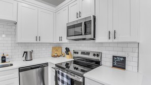 A modern kitchen with white cabinets, stainless steel appliances, and a sign indicating a WiFi password. - Spacious new 3-bedroom house in  Spartanburg (Spartanburg)