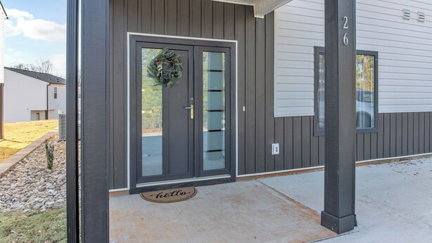 A modern house with a dark gray exterior, a glass door with a wreath, and a 'hello' mat at the entrance. - Spacious new 3-bedroom house in  Spartanburg (Spartanburg)
