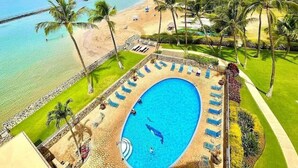 A resort with a swimming pool, beach, and palm trees.