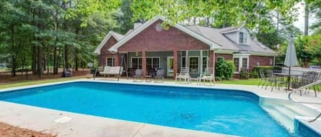 A house with a swimming pool, surrounded by trees.