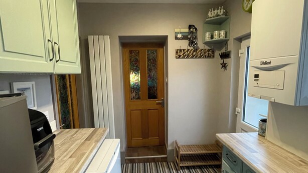 A kitchen with light blue cabinets, a striped floor, and a door leading to another room.