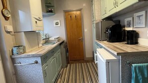 A compact kitchen with a washing machine, a coffee maker, and a refrigerator.