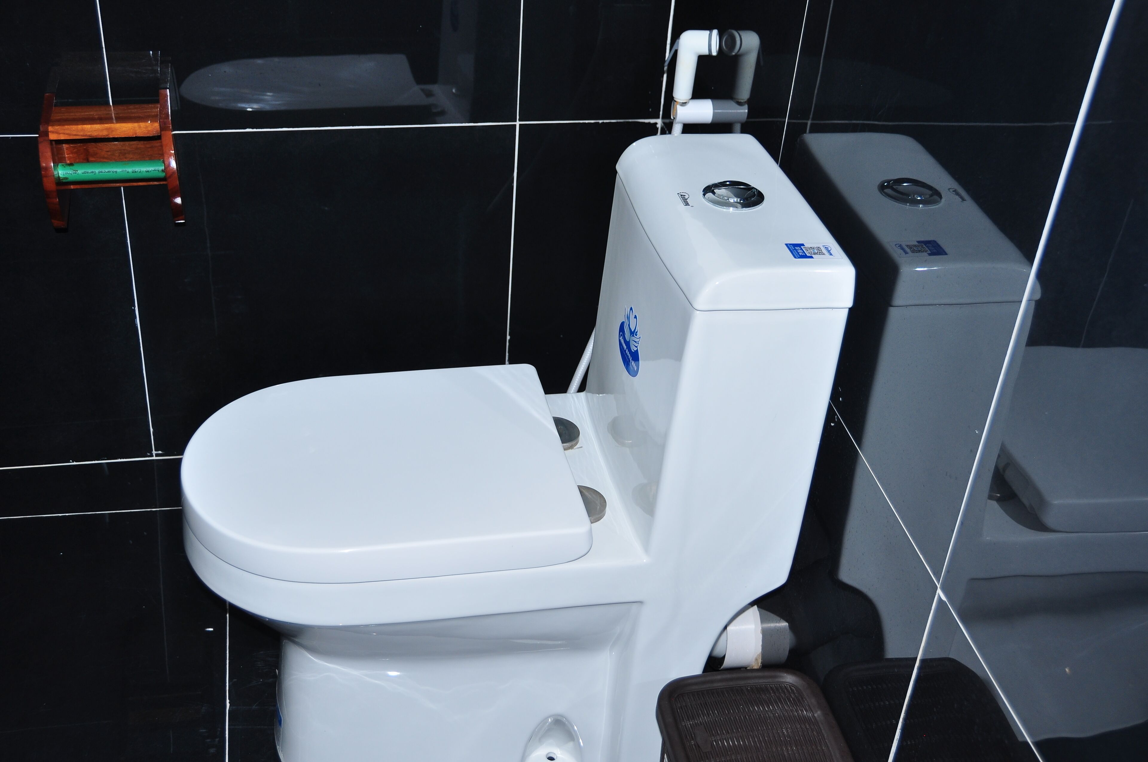 Un inodoro blanco con un pedal para los pies, un taburete de madera pequeño y un bidé blanco.