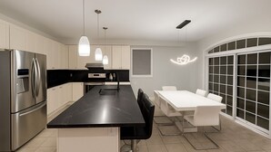 A modern kitchen with a central island, stainless steel appliances, pendant lighting, and a dining area with a white table and chairs. - 4 bedroom upper unit in Brampton (Brampton)