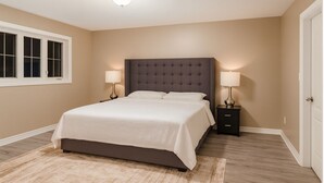 A bedroom with a large bed, two bedside tables with lamps, a window with blinds, and a door. - 4 bedroom upper unit in Brampton (Brampton)