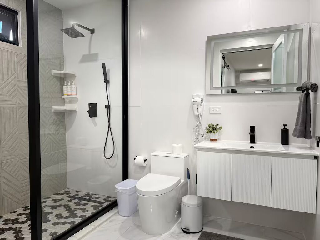 A modern bathroom with a shower, toilet, and sink.