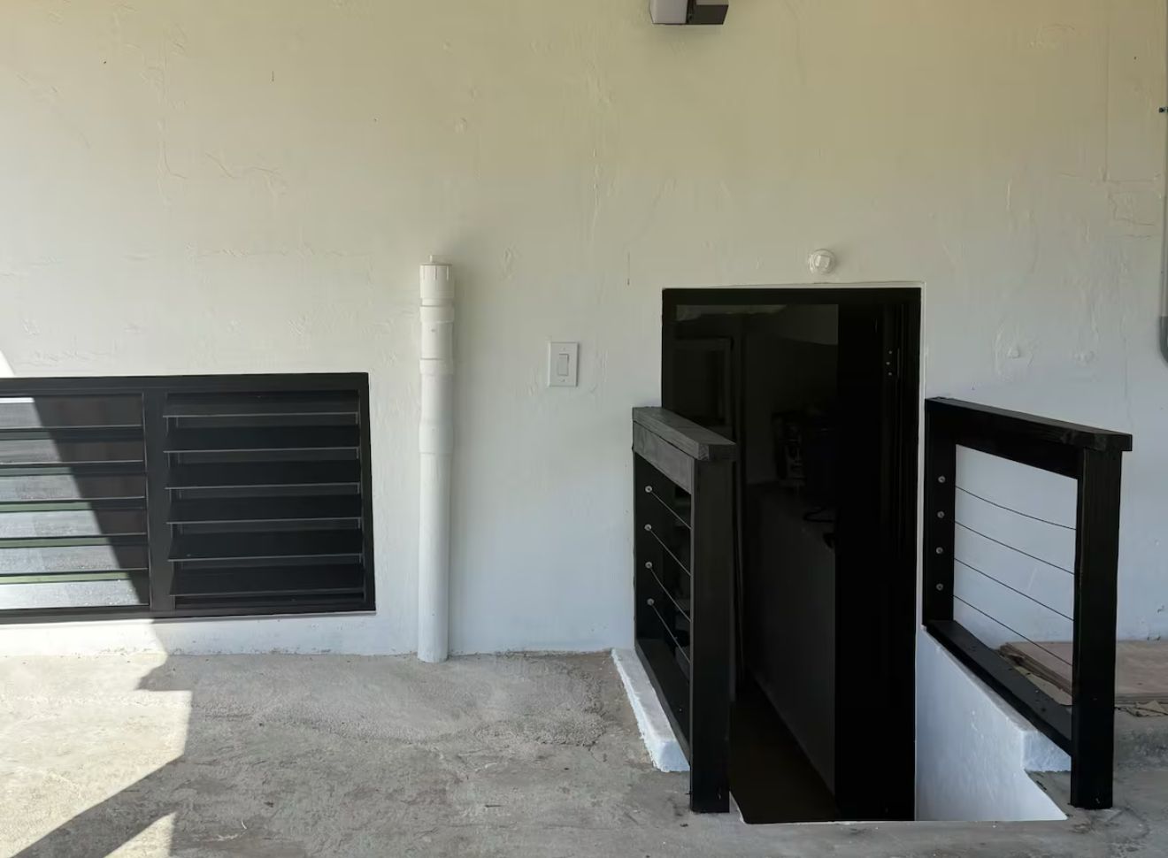 Une pièce avec un mur blanc, un portail en métal noir et un cadre de portail en métal noir.