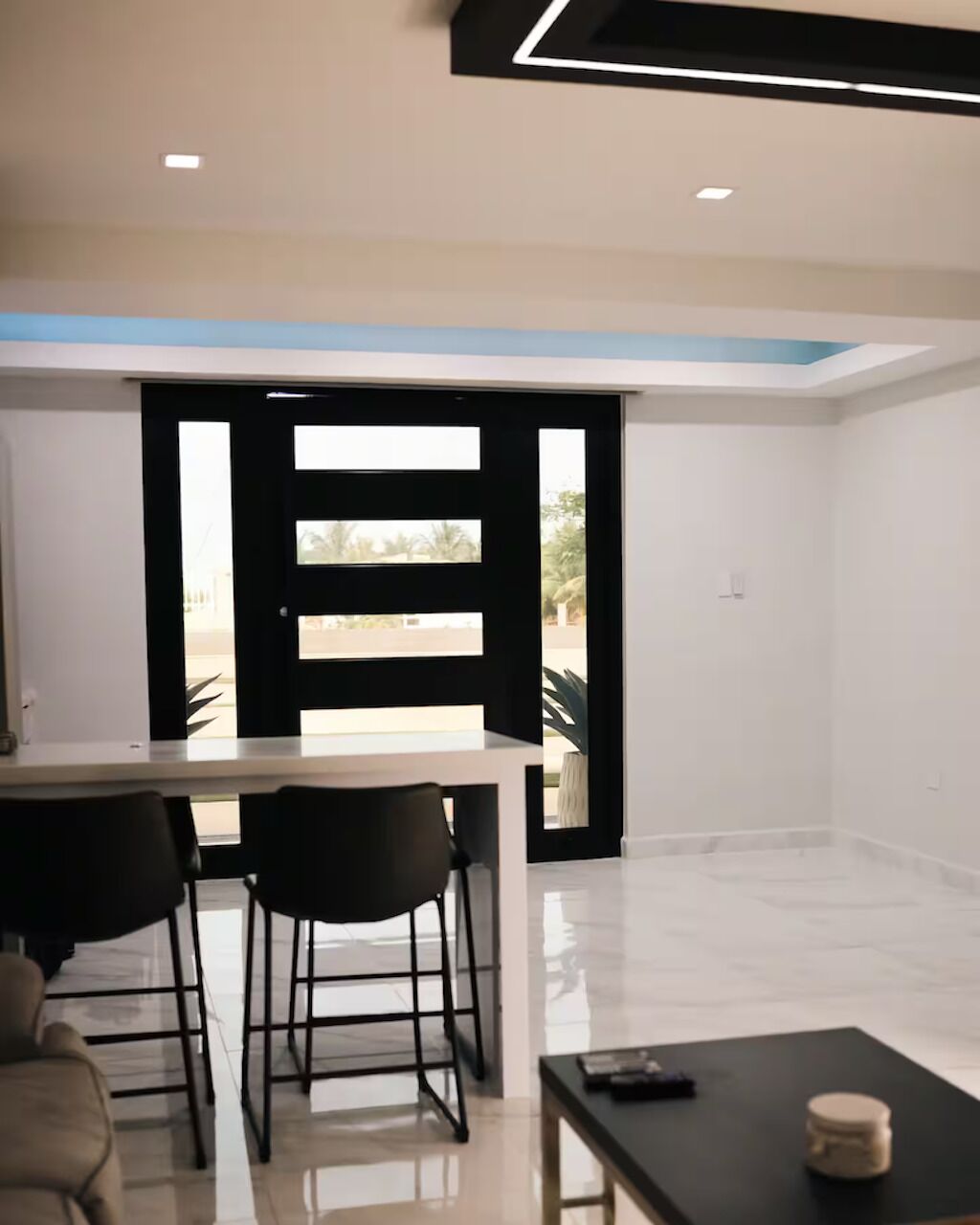 Una cocina moderna con encimera blanca, sillas negras y una mesa negra.