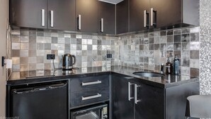 A modern kitchen with dark cabinetry, a stainless steel backsplash, and a dishwasher. - Sanctuary Hobart CBD (Hobart)