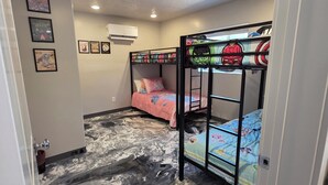 A room with bunk beds, a marble-patterned floor, and wall-mounted air conditioning.