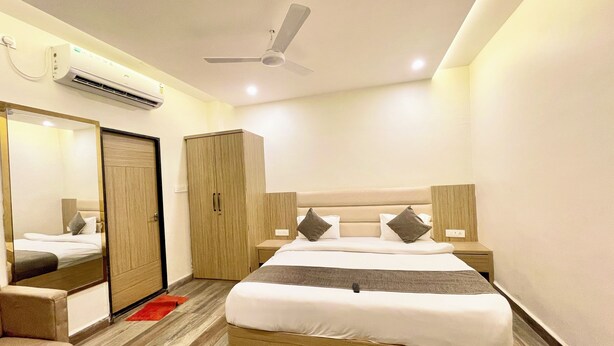 A modern hotel room with a large bed, a wardrobe, a mirror, and a ceiling fan. - P R Palace -near Temple & Prime Location (Ujjain)