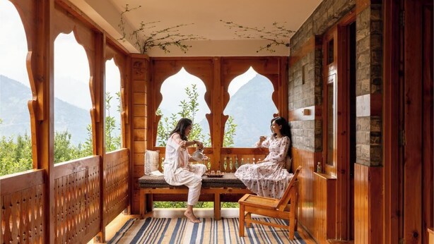 A wooden porch with a bench and a table, overlooking a mountainous landscape. - Huts And Hunters Cottage Manali (Kullu)