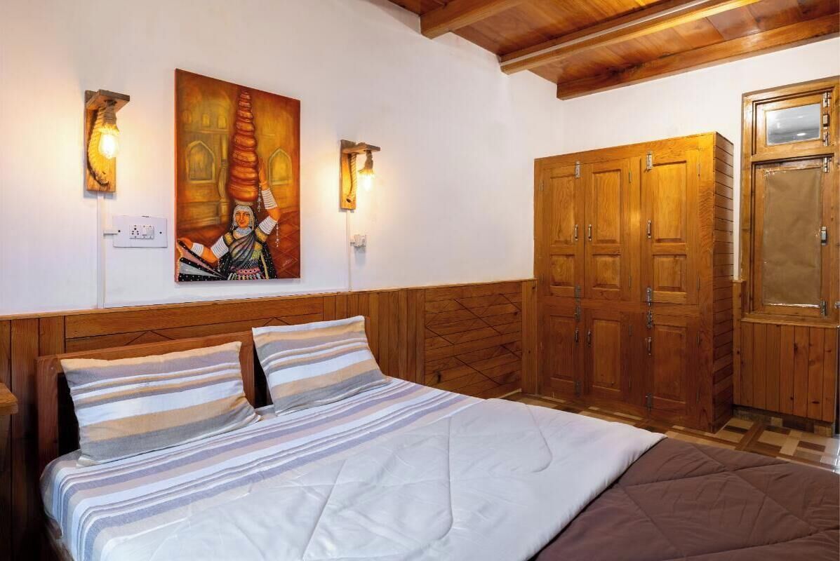 A bedroom with a bed, wooden wardrobe, and wall-mounted lights.