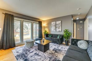 Un salon moderne avec un canapé gris, une table basse noire et un tapis à motifs.