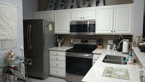 Una cocina con armarios blancos, electrodomésticos de acero inoxidable y un letrero que dice 'BEACH'.