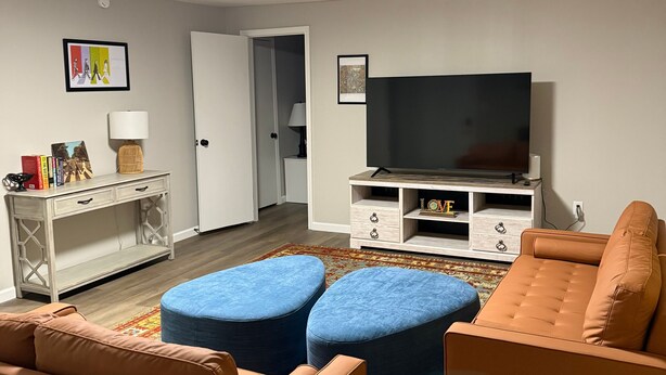 Un salón con dos sofás, un televisor, un mueble y una puerta que da a otra habitación.