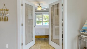 A hallway with a bed, a ceiling fan, and a view of the outdoors. - Heated Pool, Walk to Beach, 40’ Boat Dock, Kayak, Paddle Board, Fishing, $300 in Free Tickets! (St. Augustine)