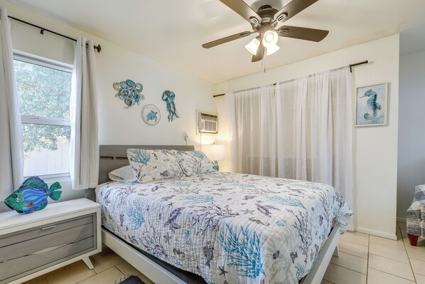 A bedroom with a bed, a nightstand, a window, a ceiling fan, and decorative wall art. - 1 Block to Dtwn! Walkable Stay in Stuart (Stuart)