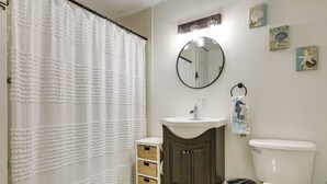 Ein Badezimmer mit weißer Duschvorhang, Waschbecken, Spiegel und Toilette.