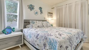 Ein Schlafzimmer mit Bett, Fenster, Deckenventilator und Wandbildern.