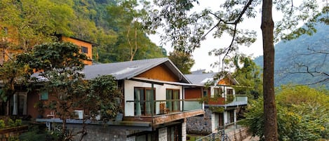 Una casa de dos pisos con base de piedra, un balcón y una escalera que lleva al nivel superior.