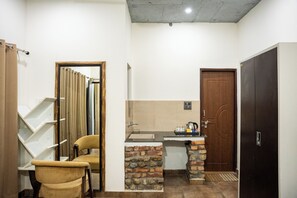 Una habitación compacta con kitchenette, puerta de madera, una silla y una cortina.