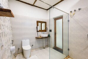 Baño con inodoro, lavabo y cabina de ducha de vidrio.