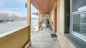 A covered outdoor area with a brick wall, a window, and a bench.
