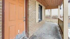 A brick building with a wooden door and a covered porch.