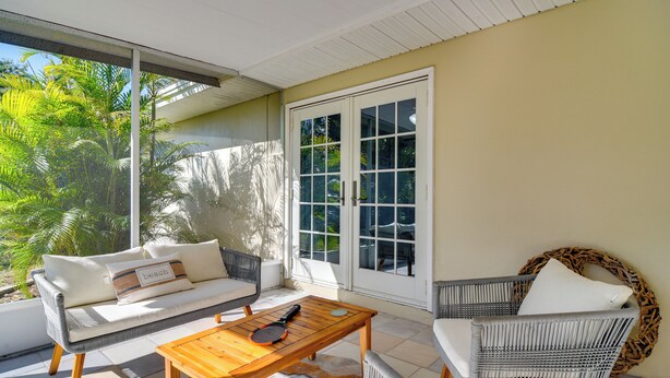A sunlit room with a sofa, a wicker chair, and a wooden table. - 4 Mi to Indian Rocks Beach: Quiet Family Escape! (Largo)