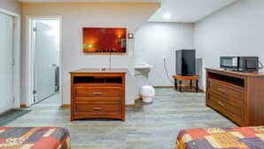 Une chambre d’hôtel avec un lit, une commode en bois, une télévision et un tableau au mur.